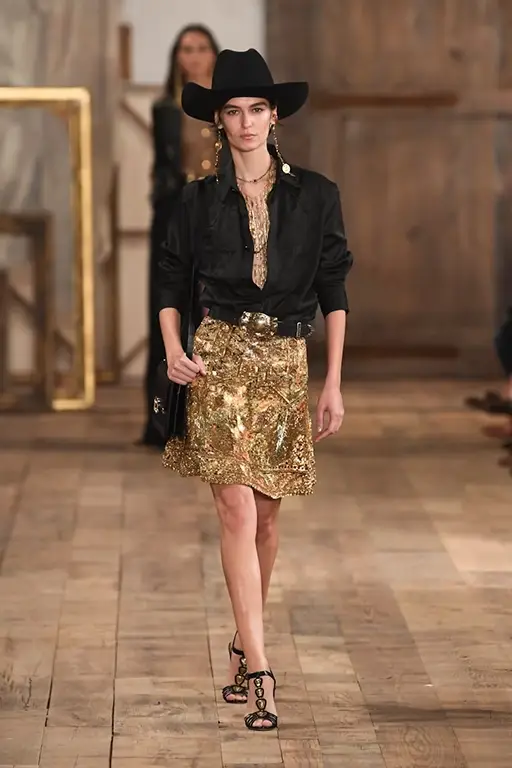  Ralph Lauren Spring 2024 styled with a Polo logo baseball cap, a gold jumpsuit, and an open shirt jacket