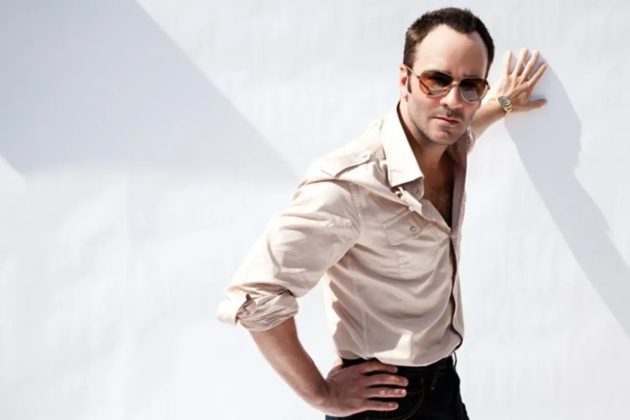 Fashion designer Tom Ford dressed in a neutral-hued fit and posing on a plain background.